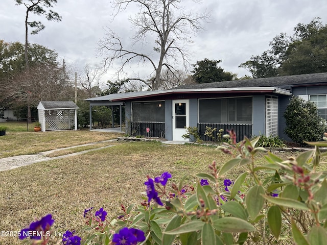 ranch-style home featuring a front yard, a carport, and a storage unit