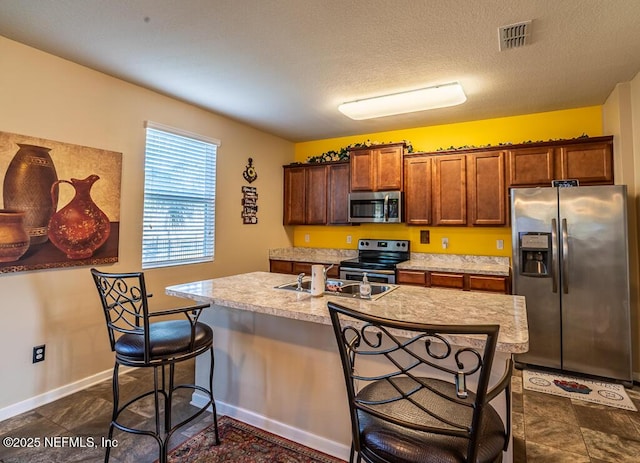 kitchen with a breakfast bar, stainless steel appliances, a center island with sink, and sink