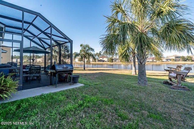 view of yard with glass enclosure, a water view, and a patio