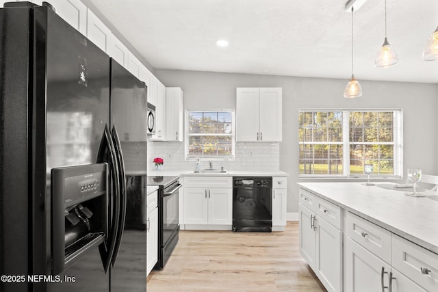 kitchen with white cabinetry, sink, hanging light fixtures, backsplash, and black appliances