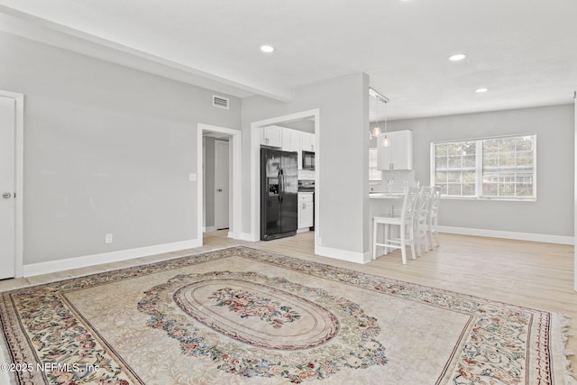 living room with beamed ceiling and light wood-type flooring