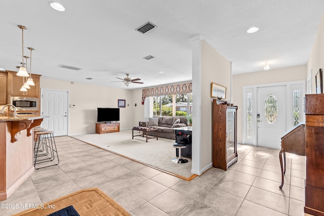 tiled living room featuring ceiling fan and sink