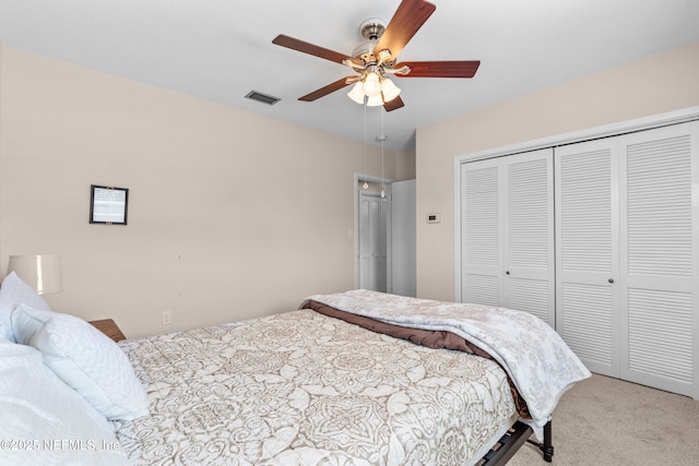 bedroom with ceiling fan, light carpet, and a closet