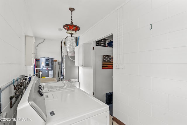 clothes washing area featuring washing machine and dryer and water heater