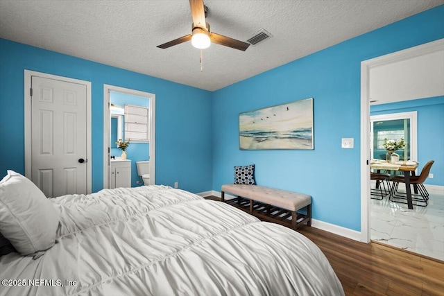 bedroom featuring ceiling fan, dark hardwood / wood-style floors, connected bathroom, and a textured ceiling