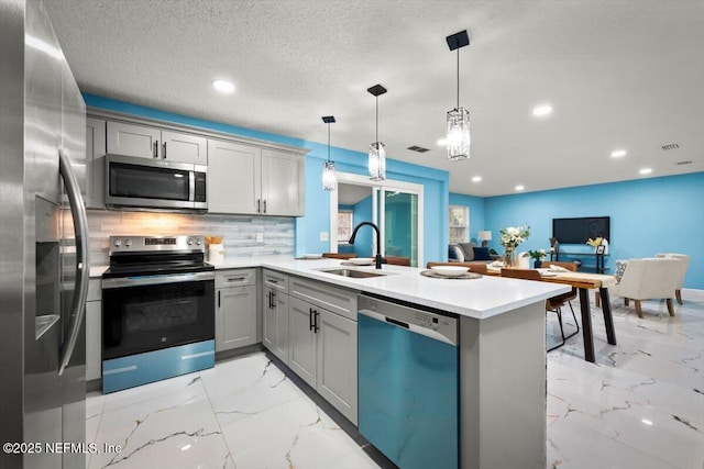 kitchen featuring sink, gray cabinets, kitchen peninsula, pendant lighting, and stainless steel appliances