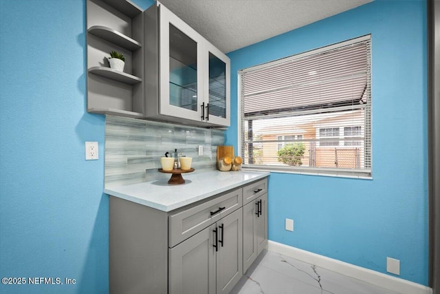 kitchen with gray cabinets, backsplash, and a textured ceiling