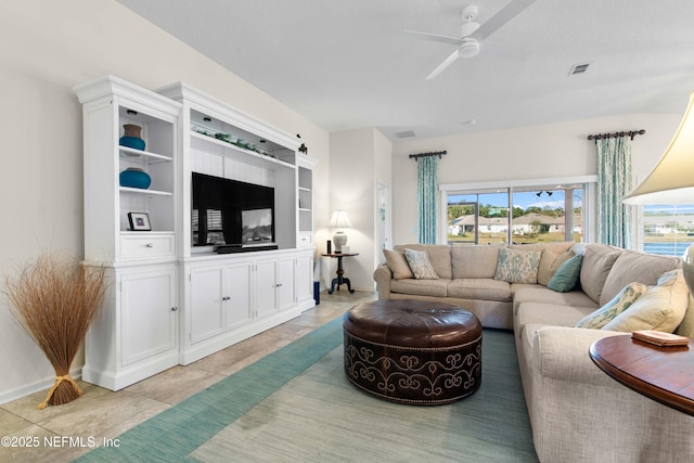 tiled living room featuring ceiling fan, built in features, and a textured ceiling