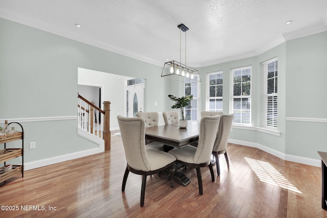 dining area featuring crown molding, light hardwood / wood-style floors, and a textured ceiling