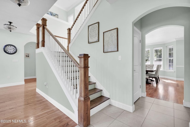 stairs with tile patterned floors and ornamental molding