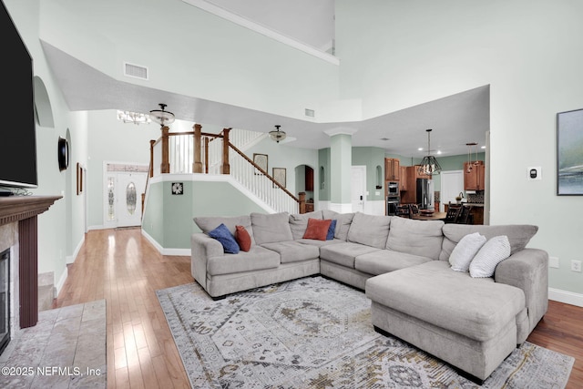 living room featuring a towering ceiling, light hardwood / wood-style flooring, and a chandelier