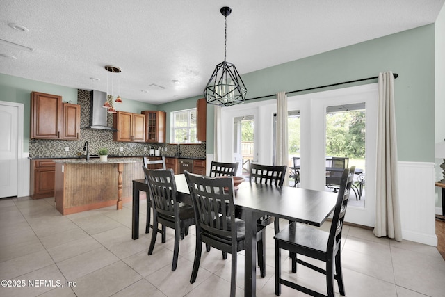 tiled dining space featuring a textured ceiling, a notable chandelier, and sink