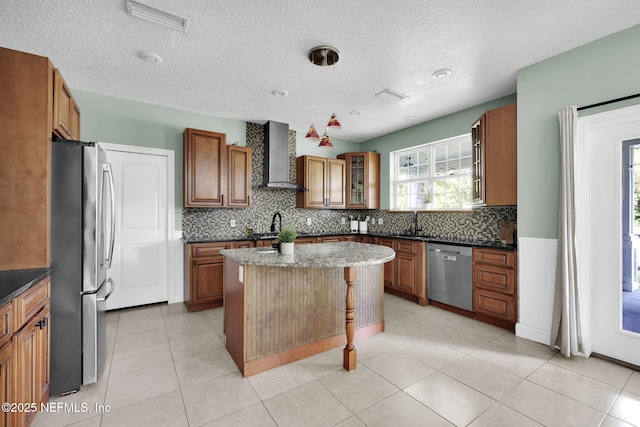 kitchen with a center island, dark stone countertops, wall chimney range hood, and stainless steel appliances