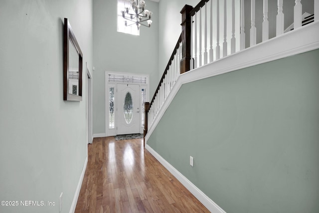 entryway with a high ceiling, a notable chandelier, and hardwood / wood-style floors