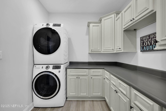 laundry area featuring light hardwood / wood-style flooring, cabinets, and stacked washer / drying machine