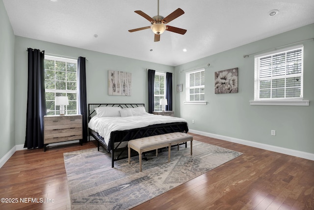 bedroom with multiple windows, dark hardwood / wood-style floors, and ceiling fan