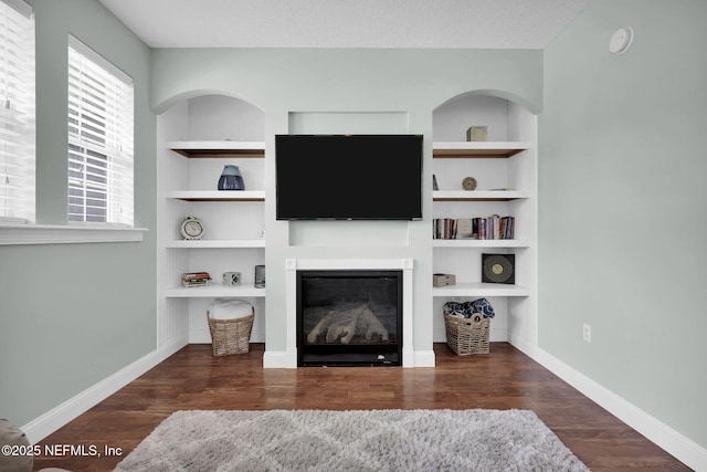 living room with dark hardwood / wood-style flooring, built in features, and a textured ceiling