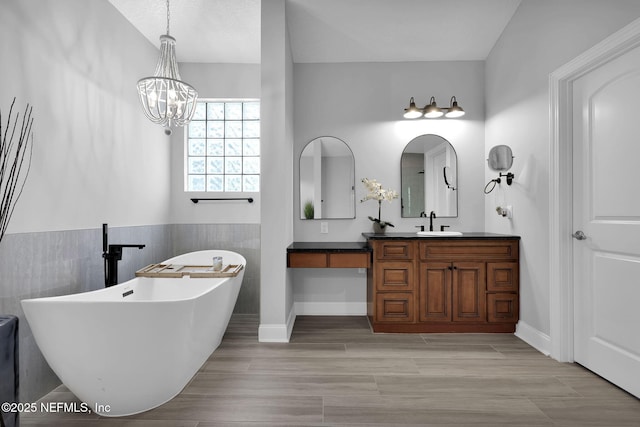 bathroom with a bathing tub, vanity, and a notable chandelier