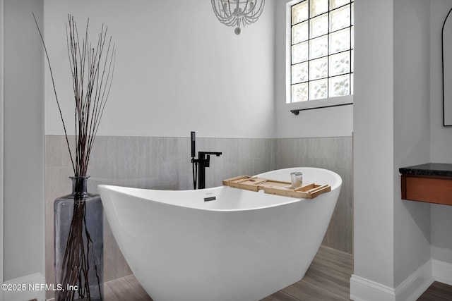 bathroom with wood-type flooring, a tub to relax in, and tile walls