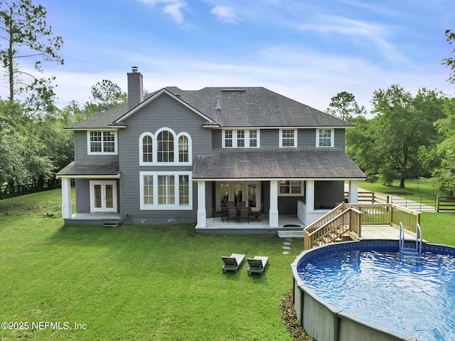 rear view of house with french doors and a lawn