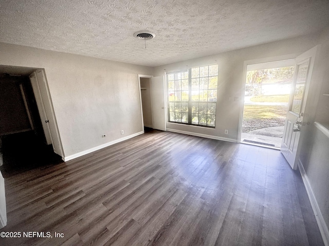 spare room featuring dark hardwood / wood-style flooring and a textured ceiling