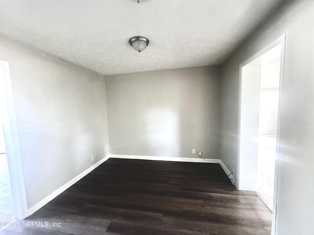 empty room with a textured ceiling and dark hardwood / wood-style flooring