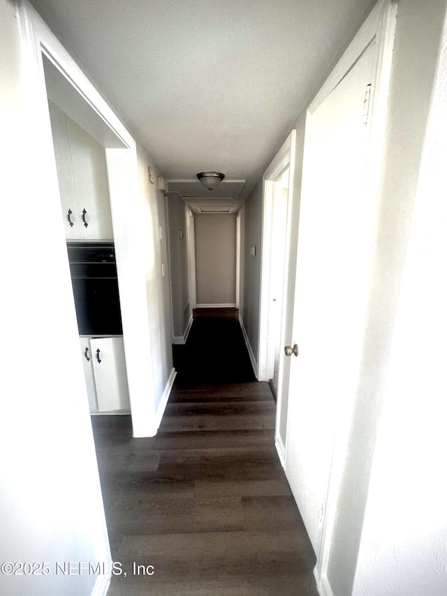 hall featuring a textured ceiling and dark hardwood / wood-style flooring