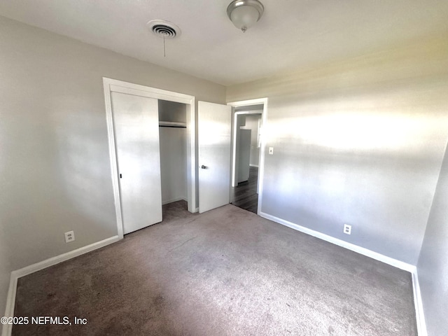 unfurnished bedroom featuring dark carpet and a closet