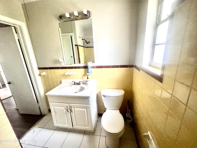 bathroom with vanity, tile patterned floors, tile walls, and toilet