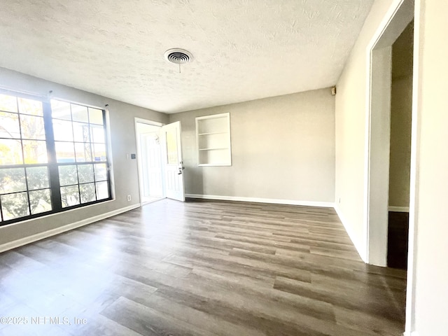 empty room with dark hardwood / wood-style floors and a textured ceiling