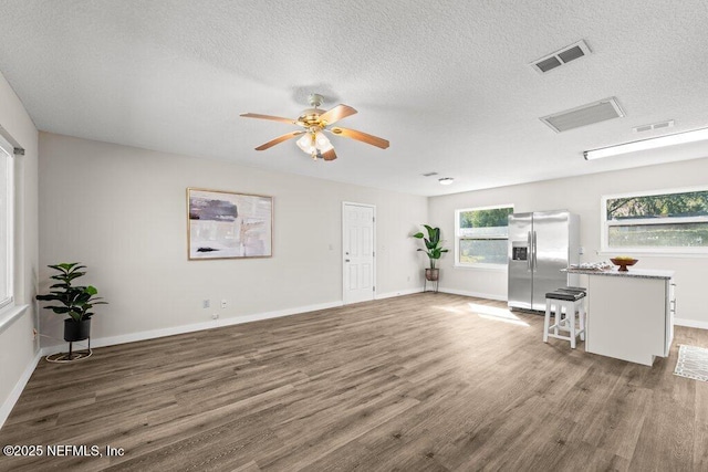 unfurnished living room featuring ceiling fan, dark hardwood / wood-style flooring, and a textured ceiling