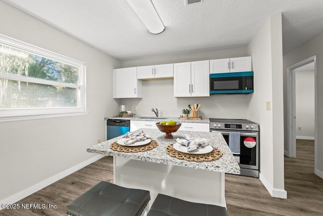 kitchen featuring appliances with stainless steel finishes, a center island, light stone countertops, white cabinets, and dark hardwood / wood-style flooring