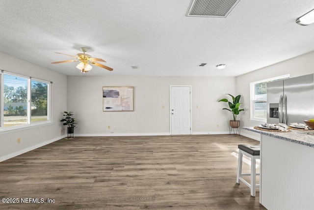 unfurnished living room featuring a textured ceiling, ceiling fan, and dark hardwood / wood-style flooring