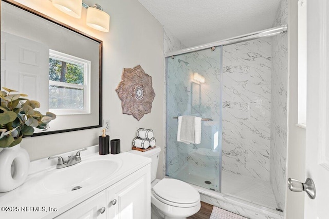 bathroom featuring a textured ceiling, toilet, vanity, and an enclosed shower