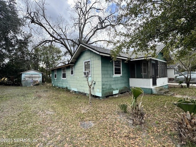 view of front of property featuring a sunroom, cooling unit, and a storage unit