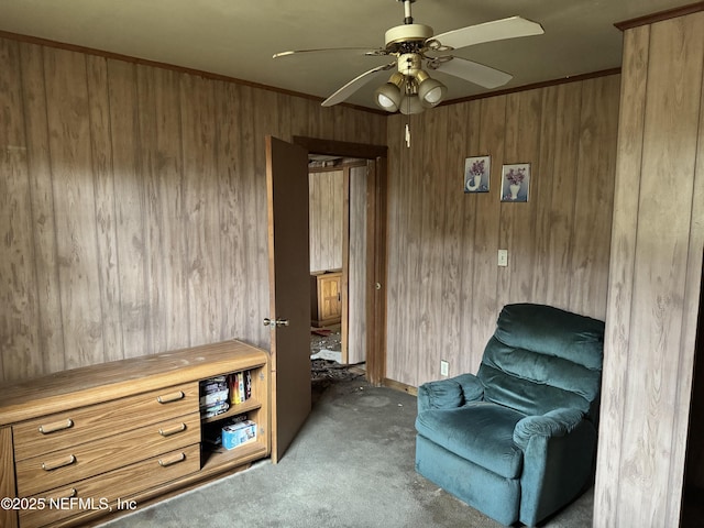 sitting room featuring light carpet, ceiling fan, and wooden walls