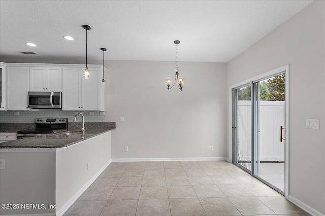 kitchen featuring pendant lighting, dark stone counters, white cabinets, sink, and stainless steel appliances