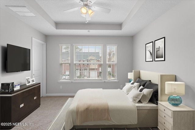 bedroom with a raised ceiling, ceiling fan, light colored carpet, and a textured ceiling