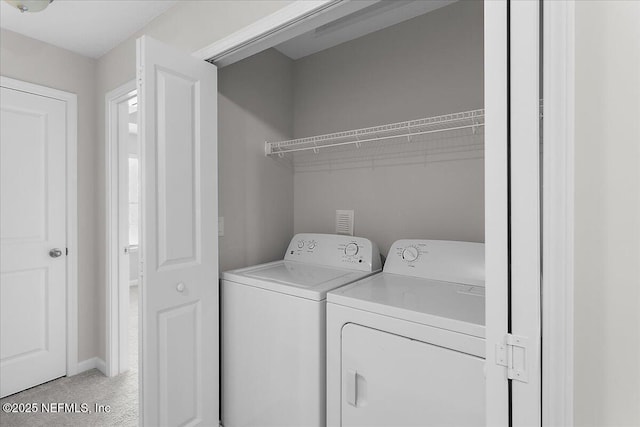 laundry room featuring light carpet and washer and clothes dryer