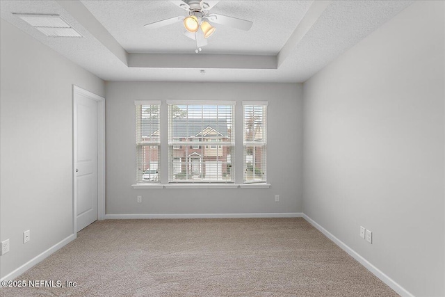 carpeted empty room featuring a textured ceiling, a tray ceiling, and ceiling fan