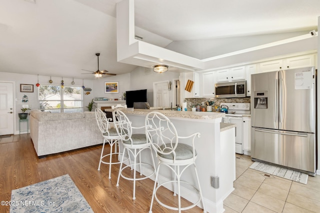 kitchen with a kitchen bar, white cabinetry, ceiling fan, and stainless steel appliances