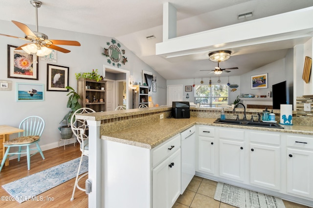 kitchen with dishwasher, white cabinets, sink, light stone countertops, and kitchen peninsula