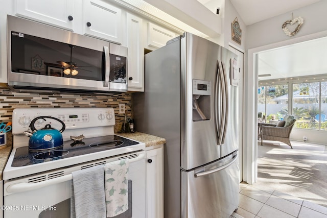 kitchen with appliances with stainless steel finishes, backsplash, ceiling fan, light tile patterned floors, and white cabinetry