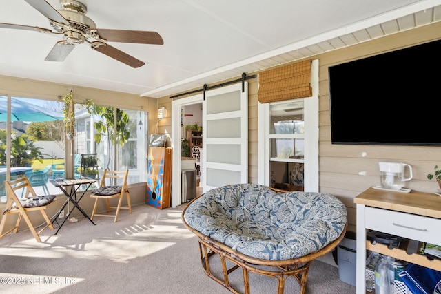 sunroom featuring a barn door and ceiling fan