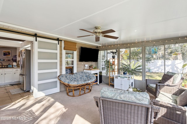 sunroom with a barn door and ceiling fan