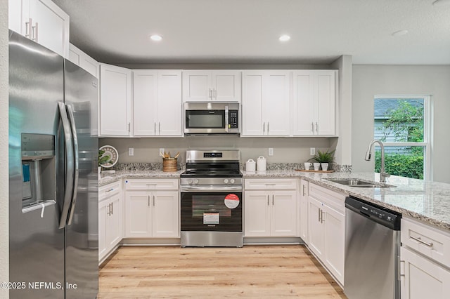 kitchen with light wood-type flooring, white cabinetry, sink, and appliances with stainless steel finishes