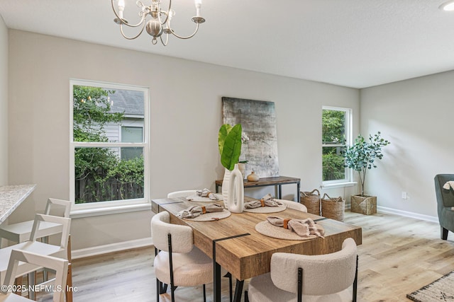 dining area with light wood-type flooring and an inviting chandelier