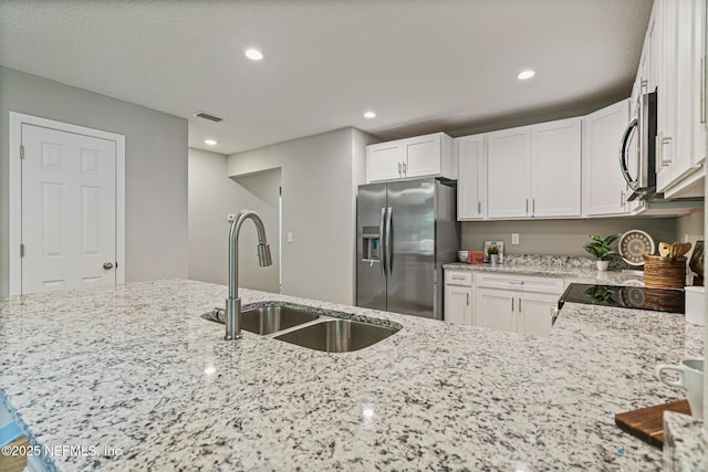 kitchen with sink, stainless steel appliances, light stone counters, kitchen peninsula, and white cabinets