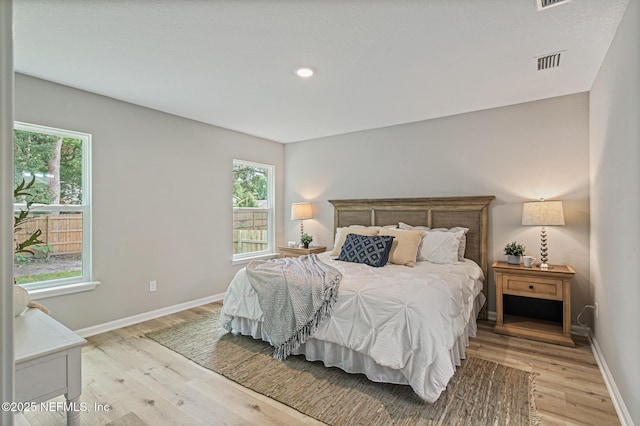 bedroom with multiple windows and light hardwood / wood-style floors