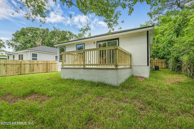 rear view of property featuring a lawn, cooling unit, and a deck